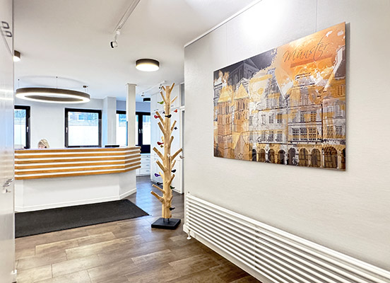 Glastür - das Wort Behandlung ist auf Dekorfollie geplottet und darauf geklebt wordedn - der Blick fällt durch die Tür auf die Lampen an der Praxisdecke im Behandlungsraum 2